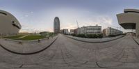 the fisheye panoramic of a street near buildings and grass as seen from a bike rack