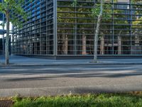 a man on his bicycle is near a building on a city street by some grass and bushes