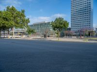 an empty street in front of a building and trees on the other side of the road