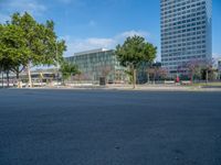 an empty street in front of a building and trees on the other side of the road