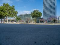 an empty street in front of a building and trees on the other side of the road