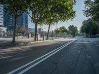 an empty street in front of a building and trees on the other side of the road