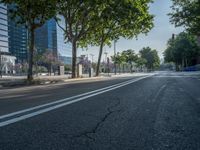 an empty street in front of a building and trees on the other side of the road