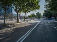 an empty street in front of a building and trees on the other side of the road