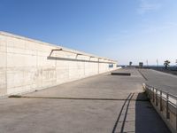 a man in black shirt doing a trick on skateboard on ramp area above cement wall with blue sky behind him