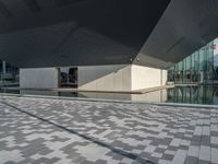 a white building next to a pool in a courtyard area with a walkway leading into it