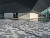 a white building next to a pool in a courtyard area with a walkway leading into it