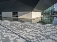 a white building next to a pool in a courtyard area with a walkway leading into it