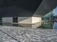 a white building next to a pool in a courtyard area with a walkway leading into it