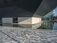 a white building next to a pool in a courtyard area with a walkway leading into it