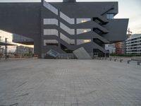 the building is very modern and large and has many square windows and is clad in grey tiles