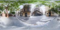 a fisheye lens view of an empty city street with trees and people walking on it