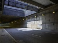 a view into a tunnel with lights in the night and an empty road underpass