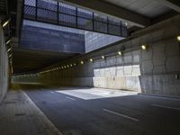 a view into a tunnel with lights in the night and an empty road underpass