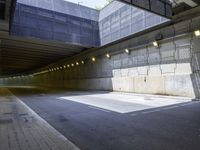 a view into a tunnel with lights in the night and an empty road underpass