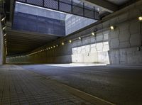 an empty walkway with lights on each end in front of a building with dark walls