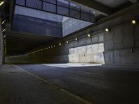 an empty walkway with lights on each end in front of a building with dark walls