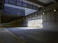 an empty walkway with lights on each end in front of a building with dark walls