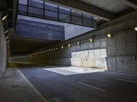 an empty walkway with lights on each end in front of a building with dark walls