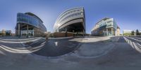 a fisheye view of several circular buildings and a man skateboarding on the road