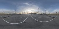 the sky is partly cloudy over an empty parking lot with buildings in the background and a building in the background