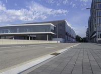 the street has two empty roads and two buildings with large windows on one side with a sky background