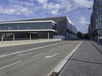 the street has two empty roads and two buildings with large windows on one side with a sky background