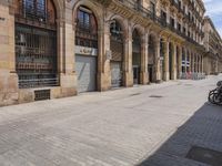 the street is empty with parked bicycles in front of the tall buildings with iron bars