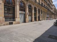 the street is empty with parked bicycles in front of the tall buildings with iron bars