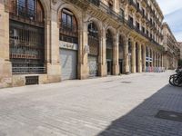 the street is empty with parked bicycles in front of the tall buildings with iron bars