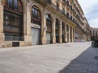 the street is empty with parked bicycles in front of the tall buildings with iron bars