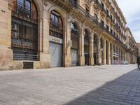 the street is empty with parked bicycles in front of the tall buildings with iron bars