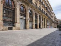 the street is empty with parked bicycles in front of the tall buildings with iron bars