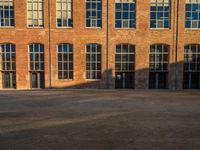 an old brick building with three open glass windows and an electric parking meter on a concrete surface