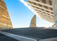 an empty asphalt road in front of an artistic structure with two steeples at either end