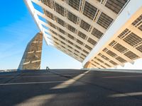 the underside of two large triangular shaped buildings in a city, one blue and one green