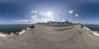 a fisheye image of the waterfront, and a parking lot and buildings in the background