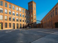 a group of brick buildings in a courtyard with trees and tall windows on each side