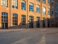 the sun shines brightly on a brick building with multiple windows and a stone courtyard