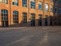 the sun shines brightly on a brick building with multiple windows and a stone courtyard