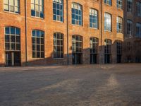 the sun shines brightly on a brick building with multiple windows and a stone courtyard