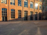 the sun shines brightly on a brick building with multiple windows and a stone courtyard