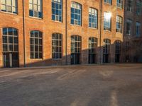 the sun shines brightly on a brick building with multiple windows and a stone courtyard