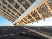 the roof on a long bridge is made of windows and a street light that lights up over the walkway