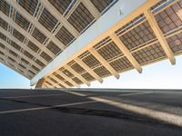 the roof on a long bridge is made of windows and a street light that lights up over the walkway