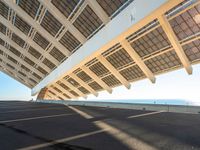 the roof on a long bridge is made of windows and a street light that lights up over the walkway