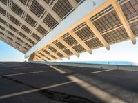 the roof on a long bridge is made of windows and a street light that lights up over the walkway