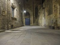 an old stone walkway in front of a doorway with blue door and brick walls leading into a room with tall windows