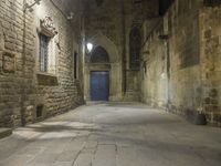 an old stone walkway in front of a doorway with blue door and brick walls leading into a room with tall windows