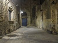 an old stone walkway in front of a doorway with blue door and brick walls leading into a room with tall windows